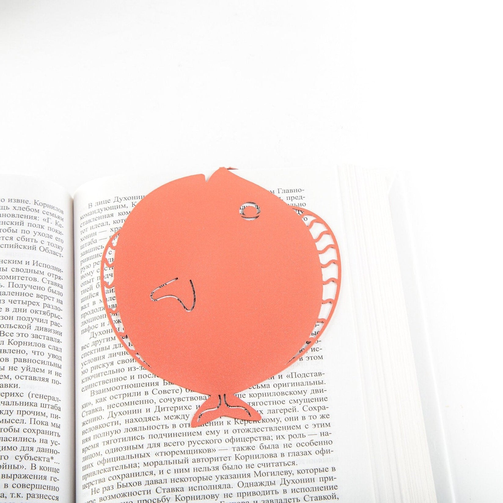 Flounder metal bookmark in red resting on the pages of an open book