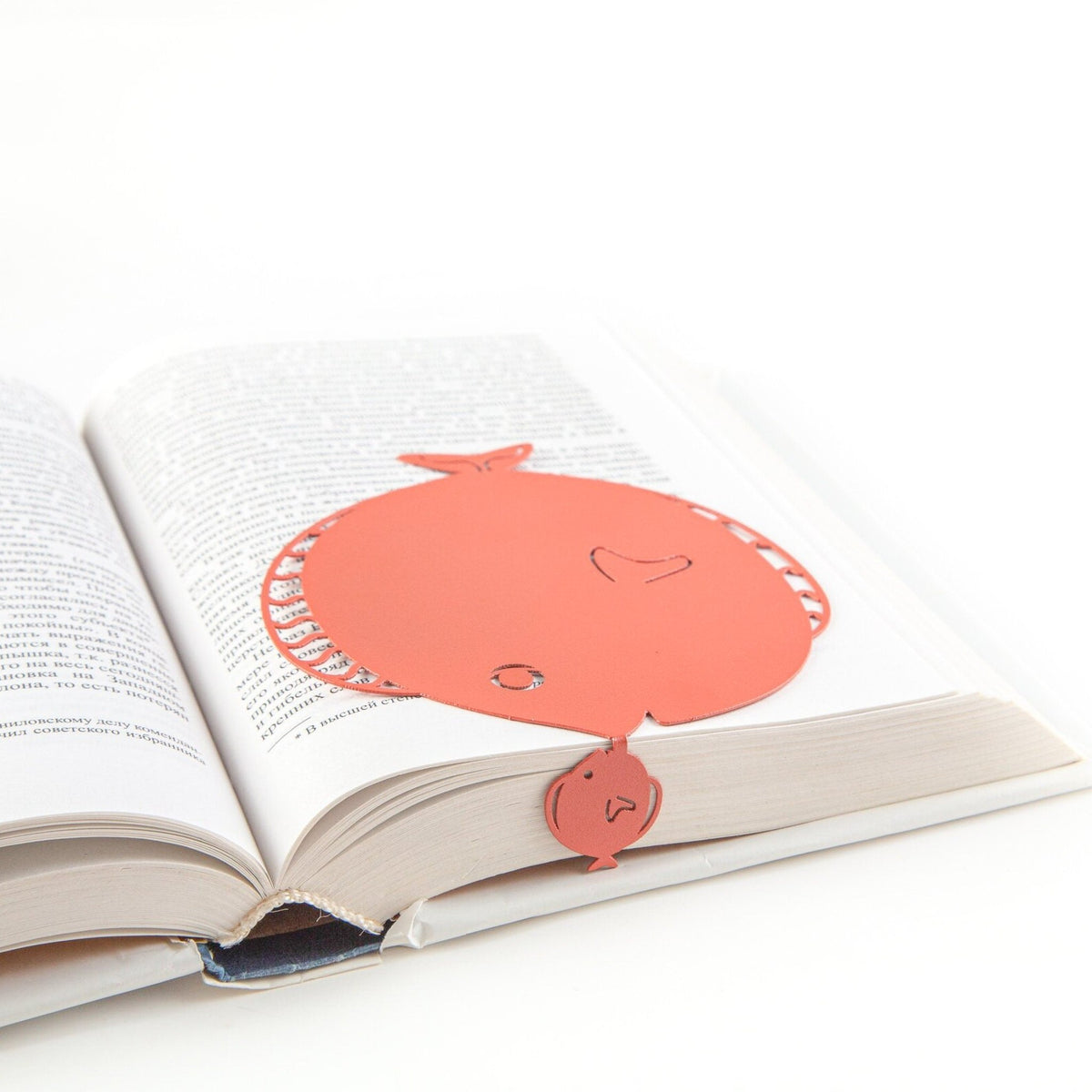 Flounder metal bookmark in red marking a page in an open book