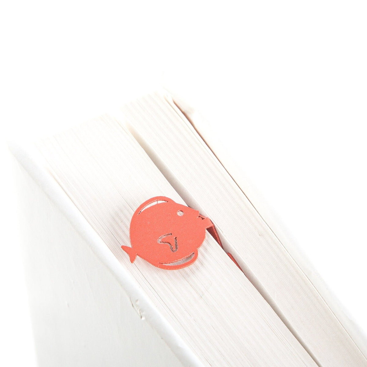 Flounder metal bookmark in red seen from the edge of a closed book