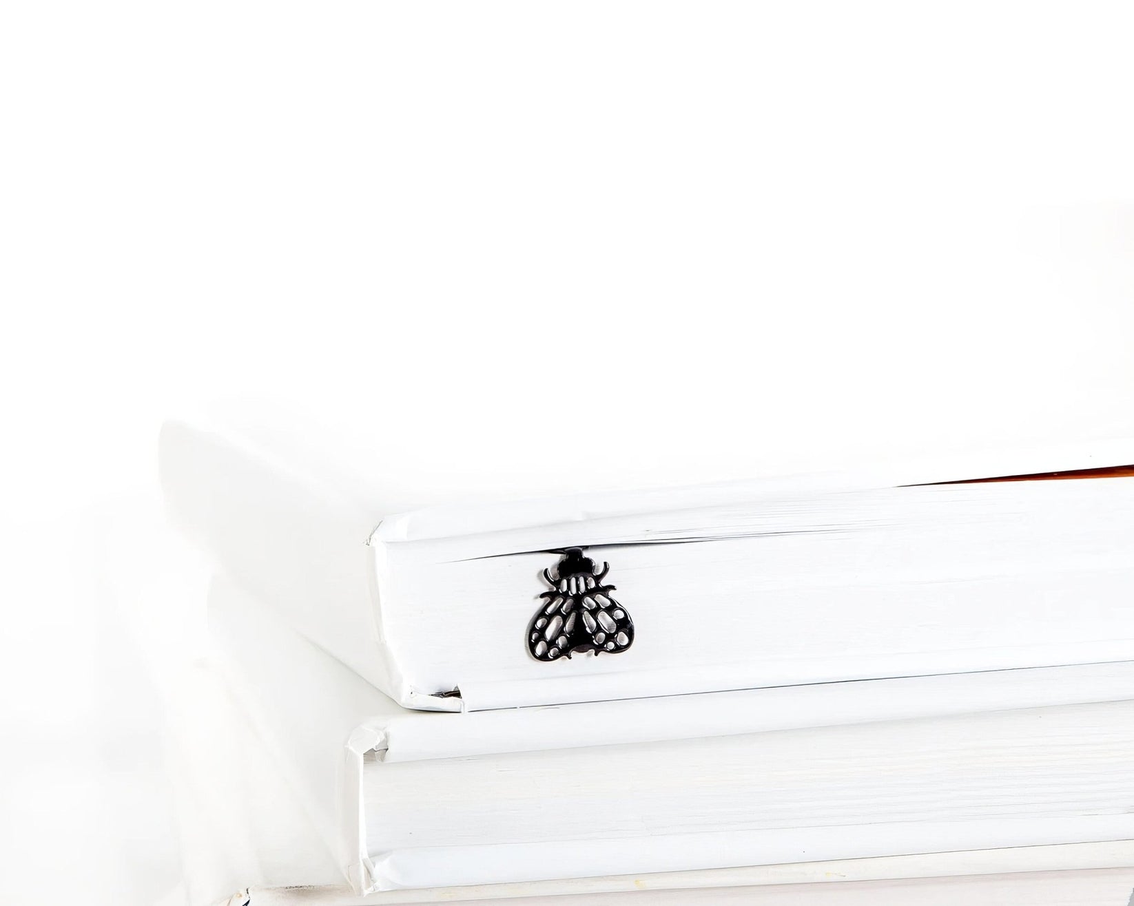Fly metal bookmark clipped in a closed book, viewed from the side