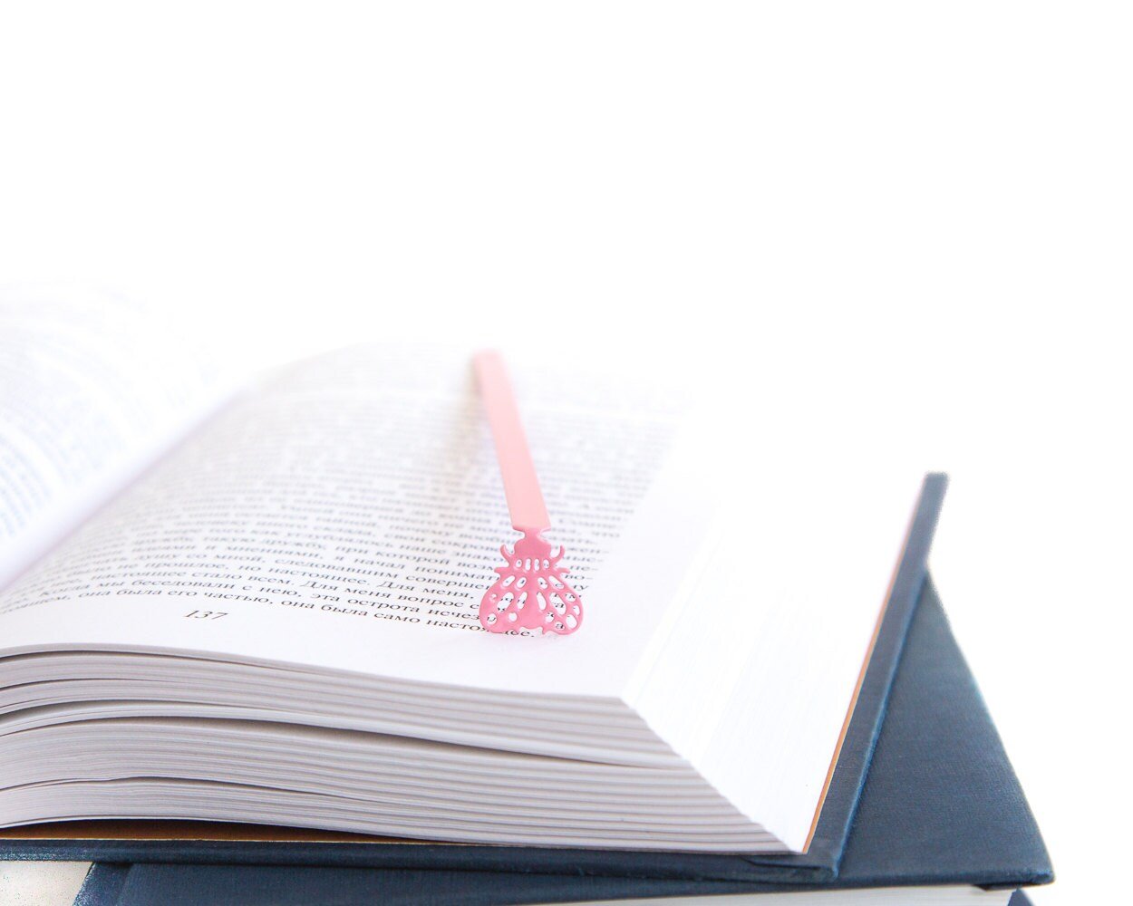 Fly metal bookmark in red resting on the pages of an open book