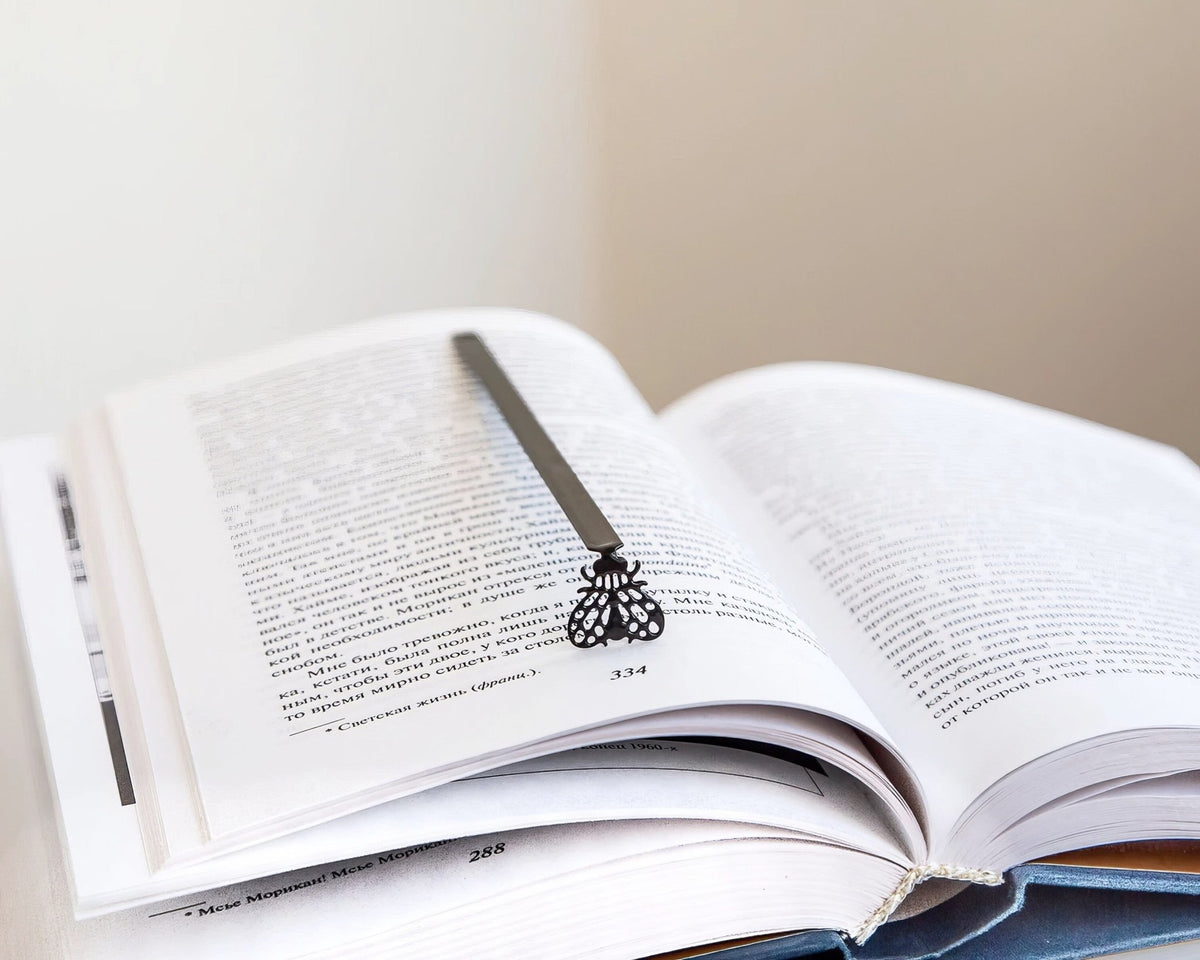 Fly metal bookmark marking a page in an open book