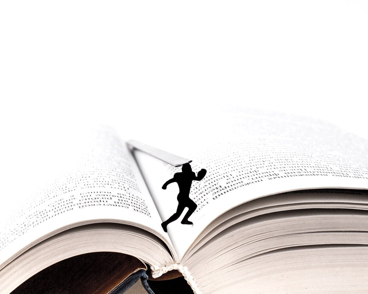 Football Player metal bookmark resting on the pages of an open book