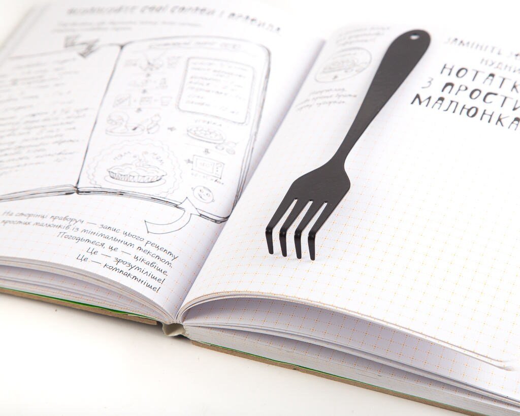 Fork metal bookmark marking a page in an illustrated book