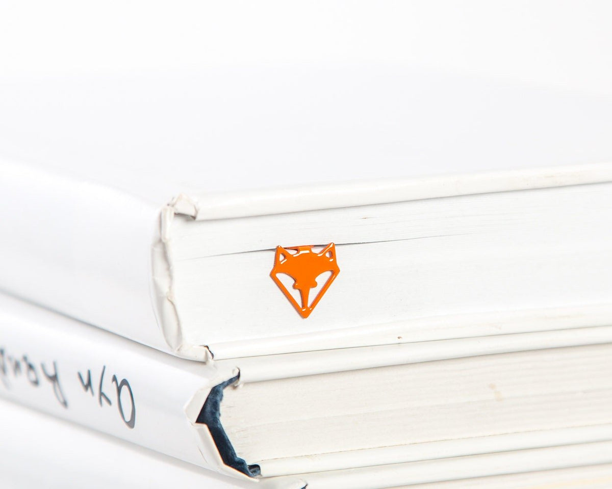 Fox Head metal bookmark in red in a closed book, only its top showing above the pages