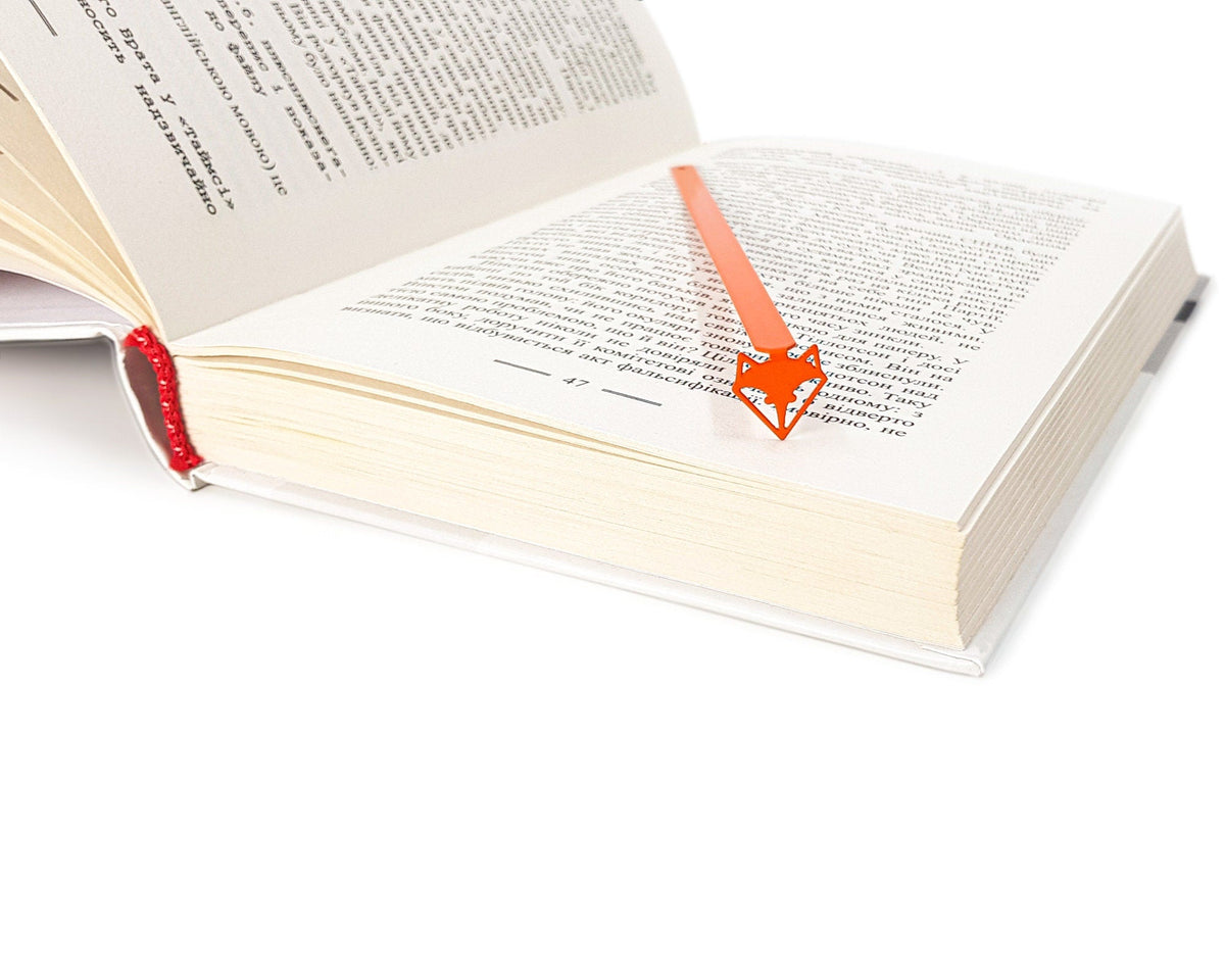 Fox Head metal bookmark in red seen from the edge of a closed book