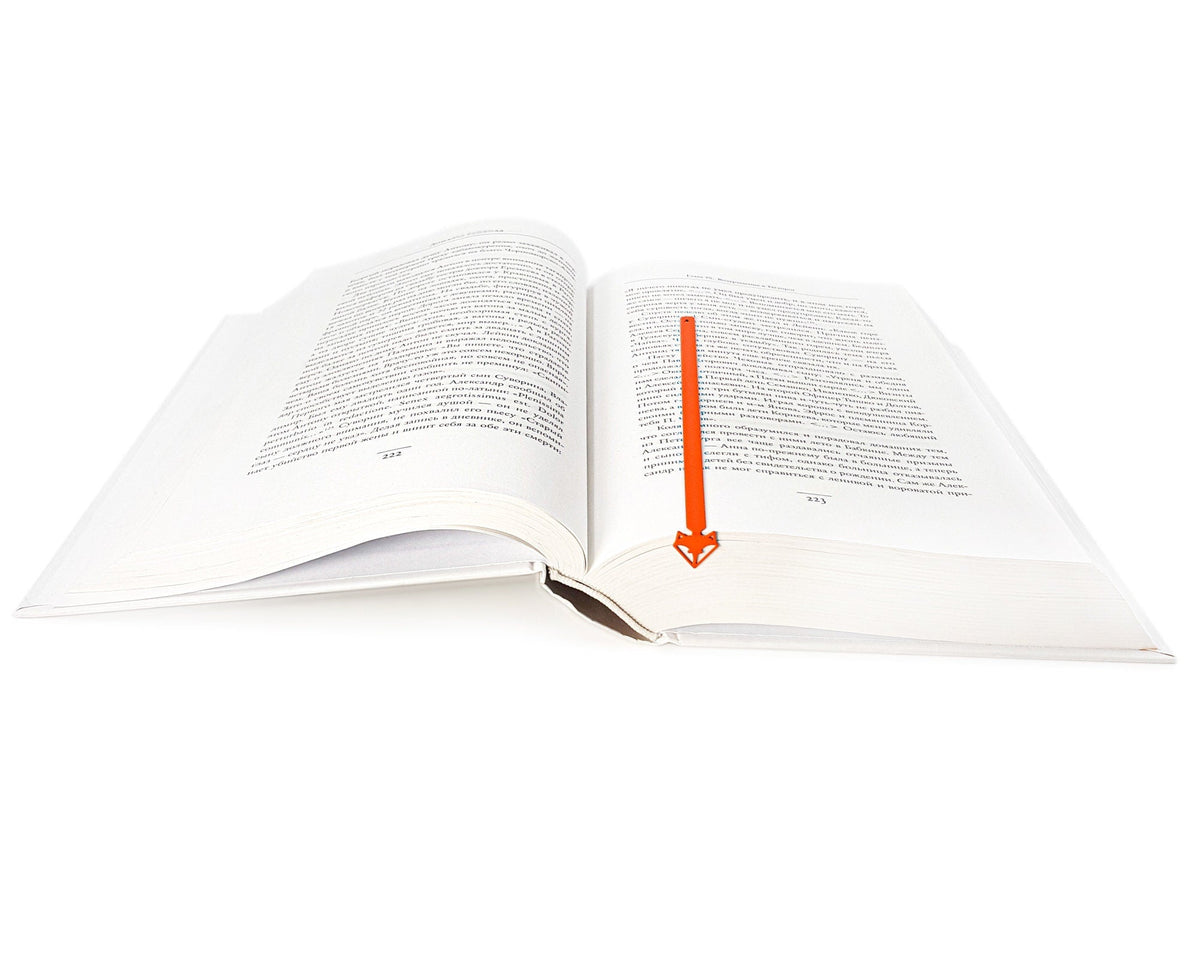 Fox Head metal bookmark in red lying across the pages of an open book