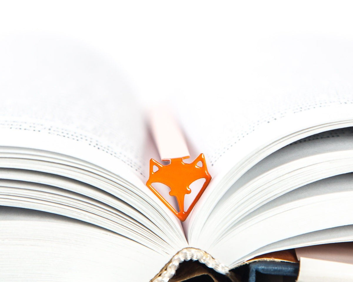 Fox Head metal bookmark in red resting on the pages of an open book