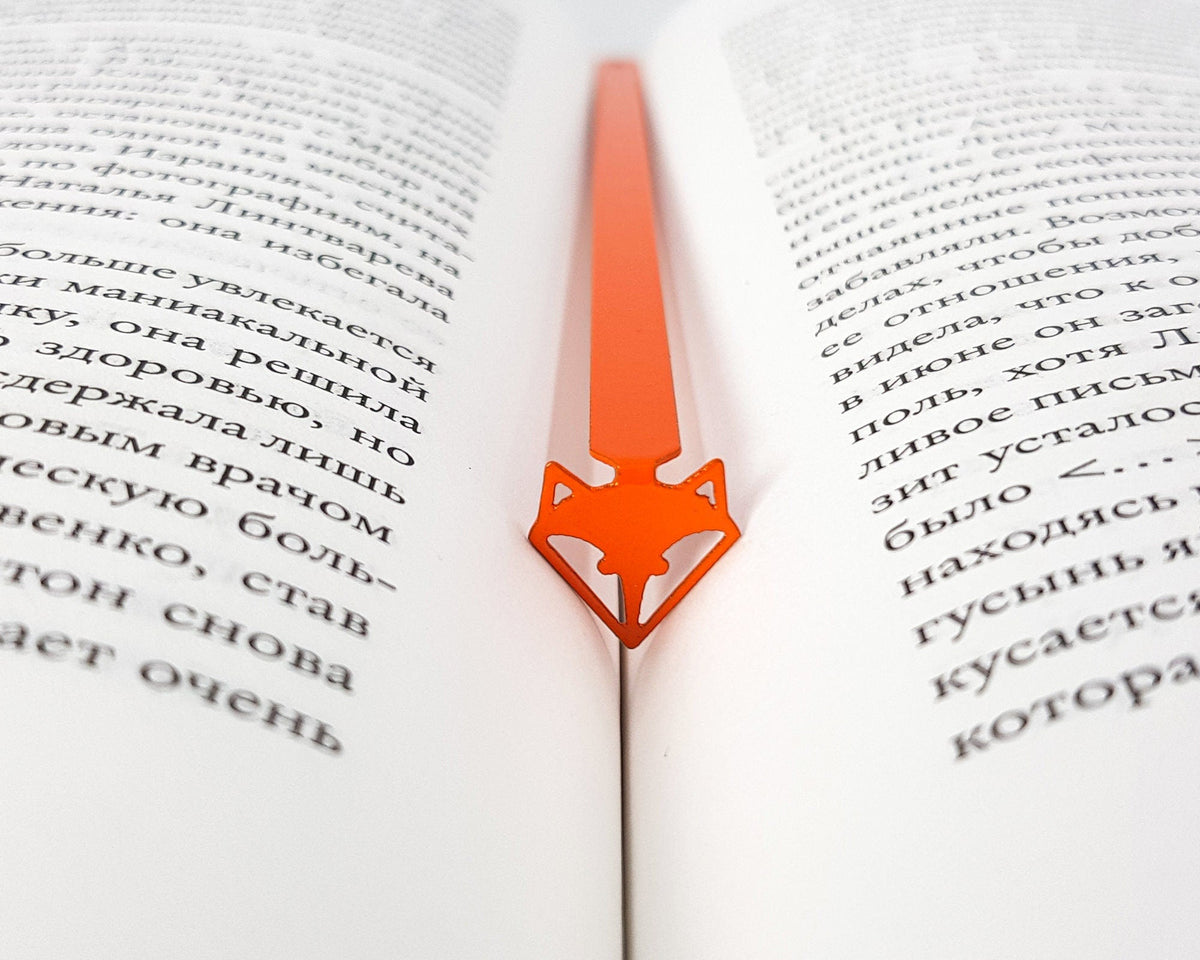 Fox Head metal bookmark in red set into the gutter of an open book