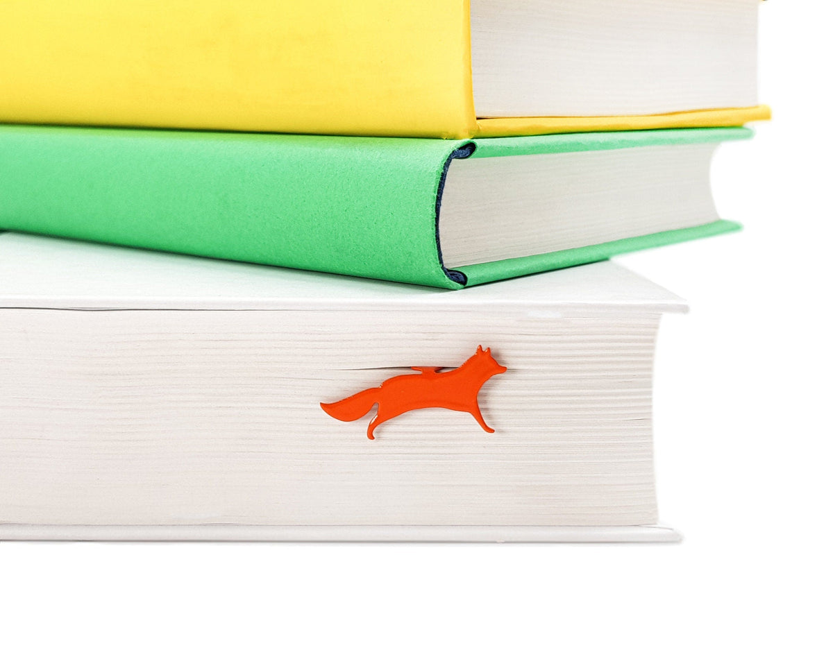 Fox on the Run metal bookmark in red shown with a stack of books