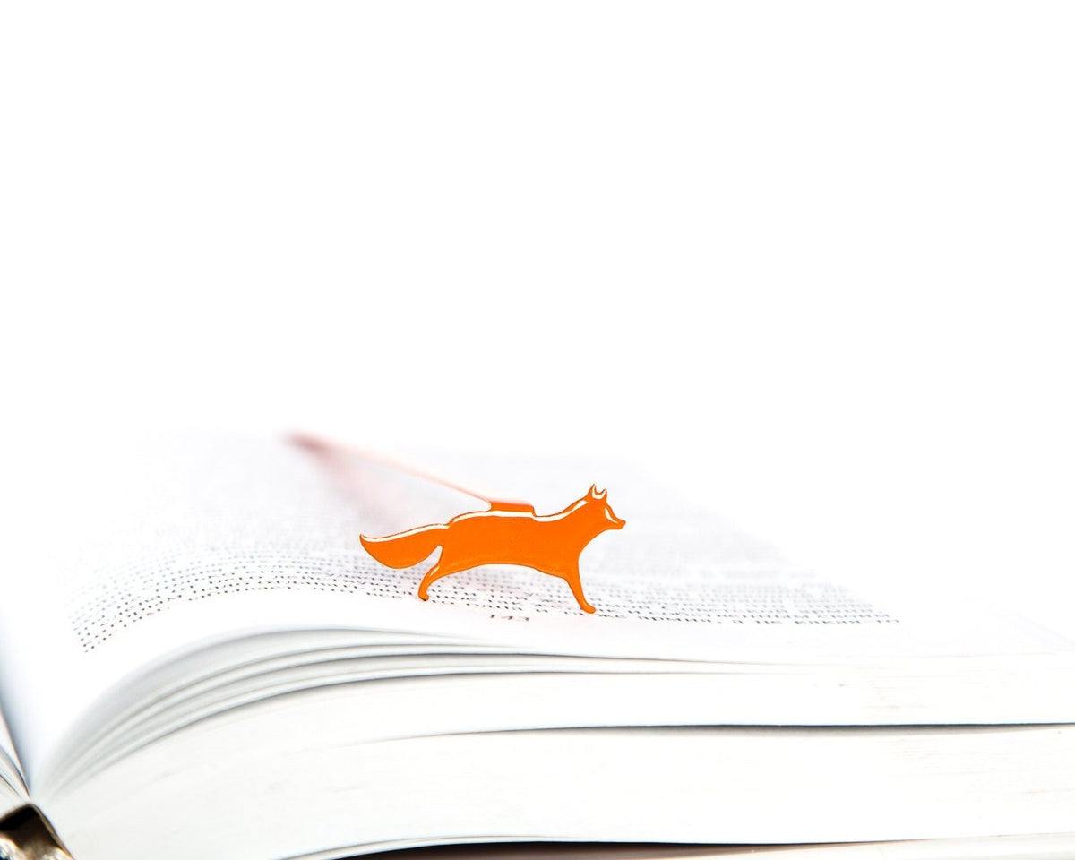 Fox on the Run metal bookmark in red marking a page in an open book