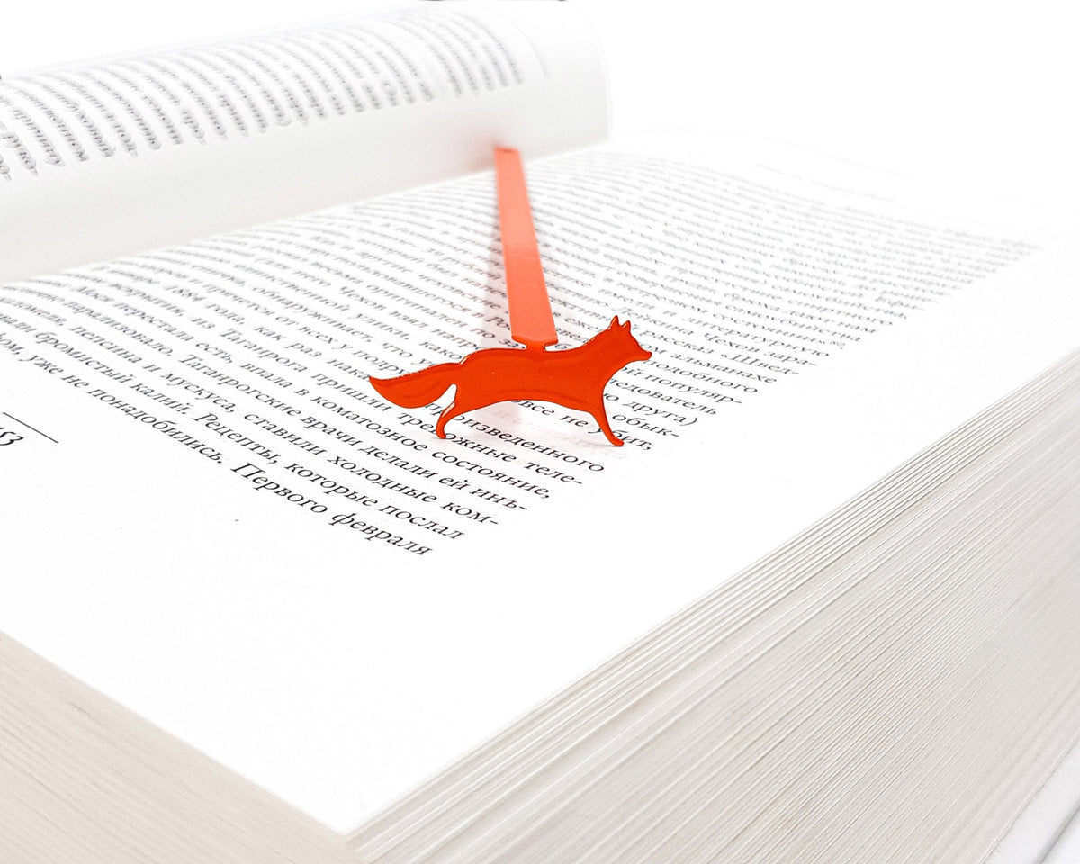Fox on the Run metal bookmark in red resting on the pages of an open book