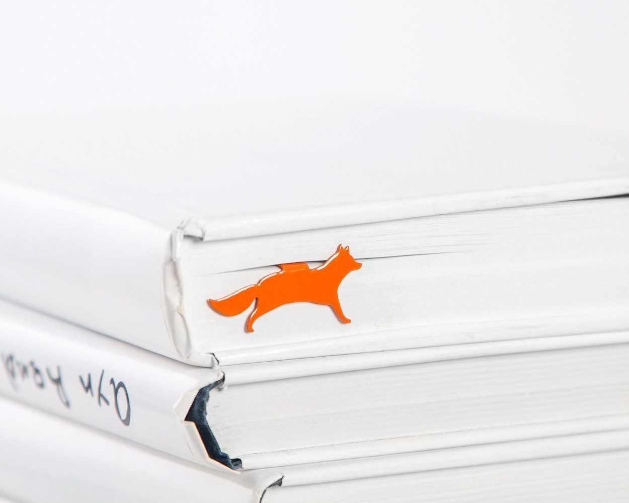 Fox on the Run metal bookmark in red in a closed book, only its top showing above the pages