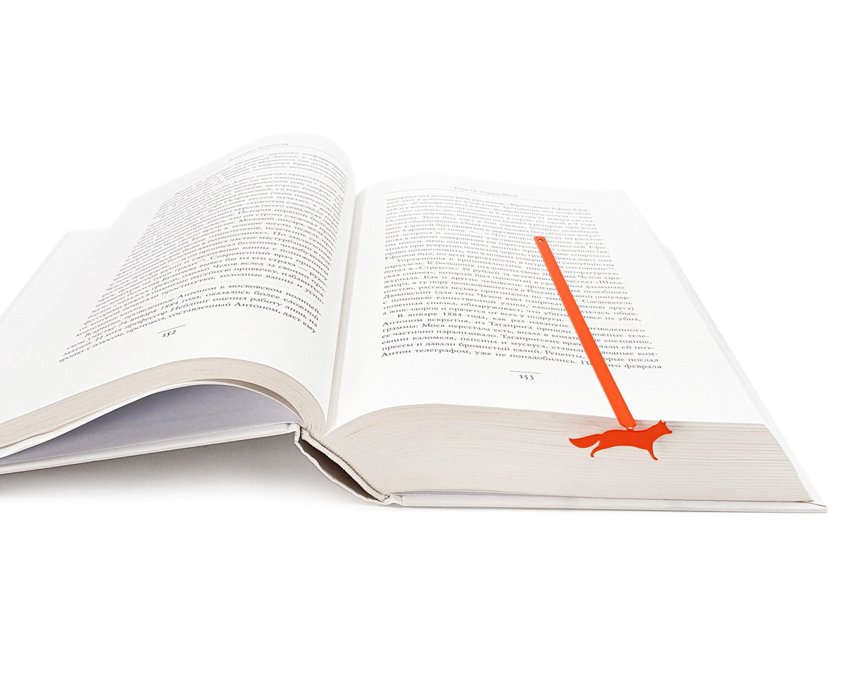 Fox on the Run metal bookmark in red lying across the pages of an open book