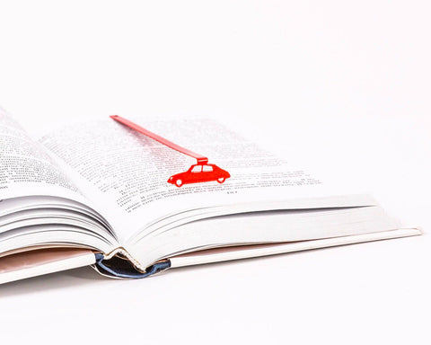 French Car metal bookmark in red resting on the pages of an open book