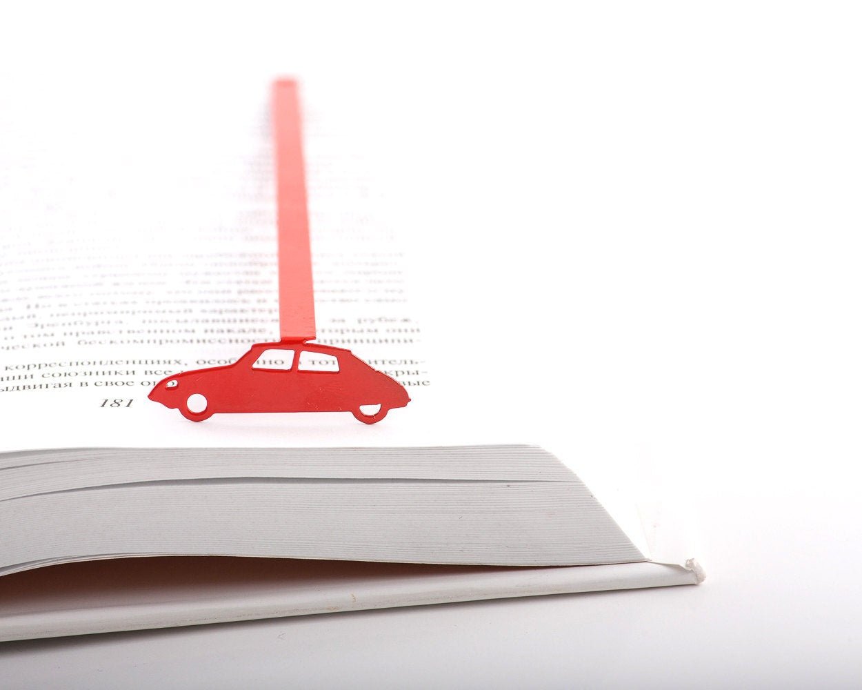 French Car metal bookmark in red in a closed book, only its top showing above the pages