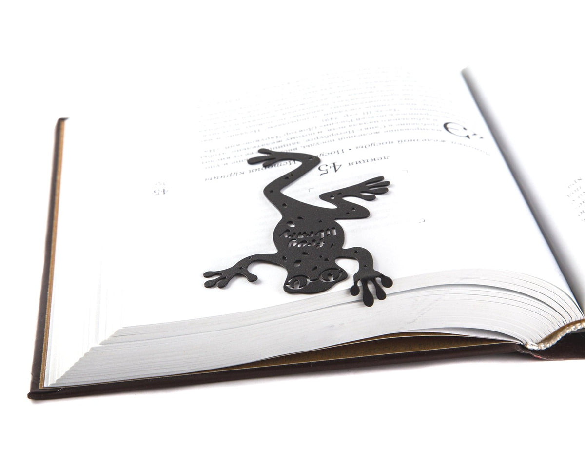 Frog Library metal bookmark marking a page in an open book