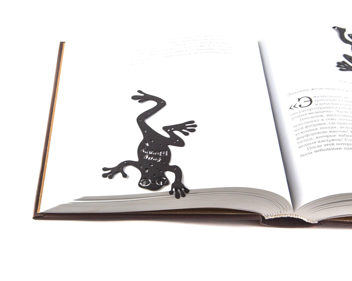 Frog Library metal bookmark resting on the pages of an open book, view 5