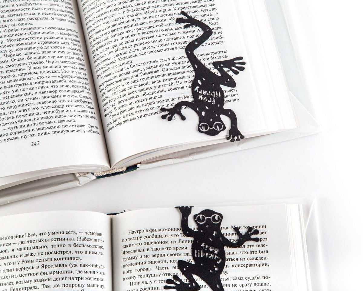 Frog Library metal bookmark lying across the pages of an open book