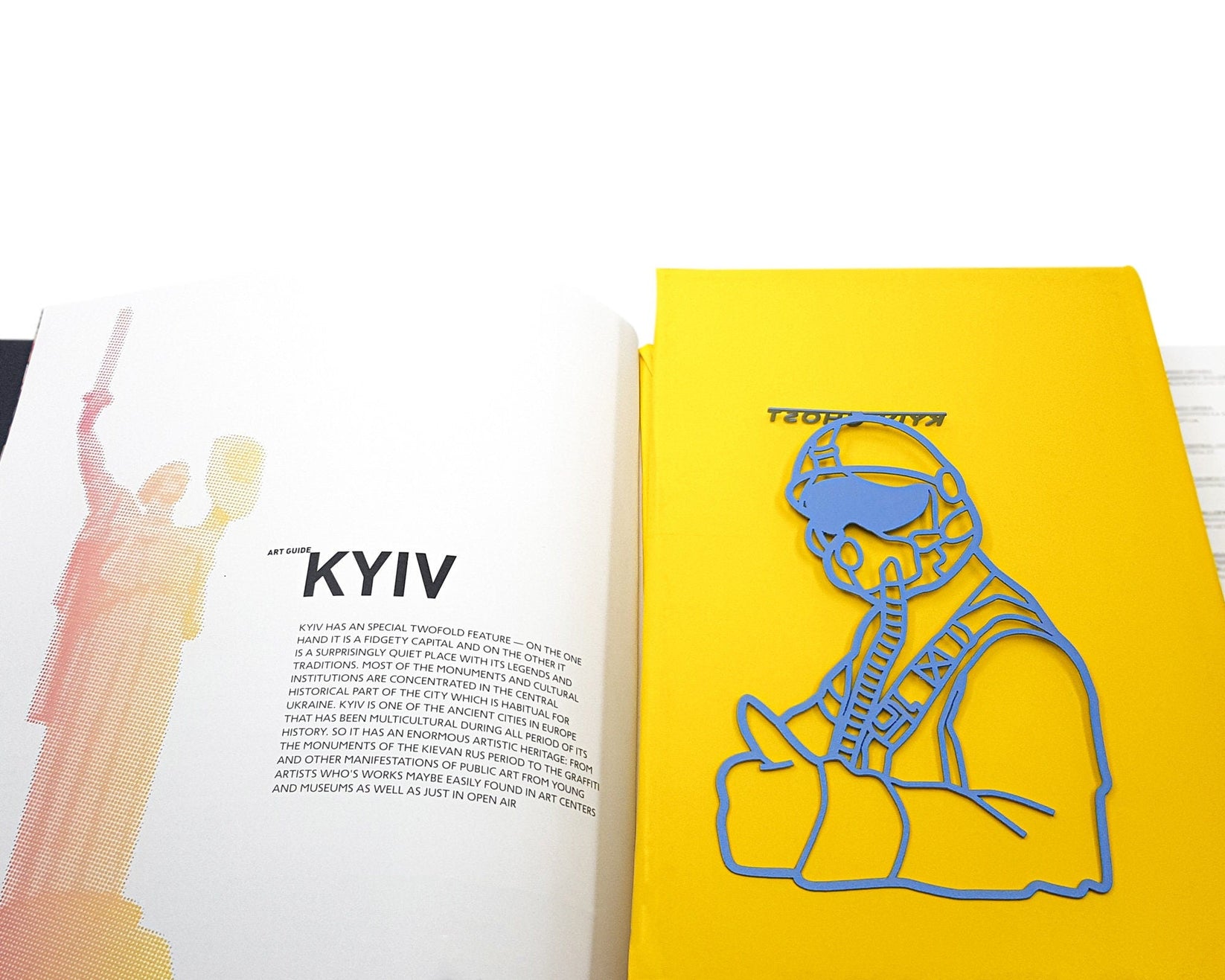 Ghost of Kyiv metal bookmark in blue resting on the pages of an open book