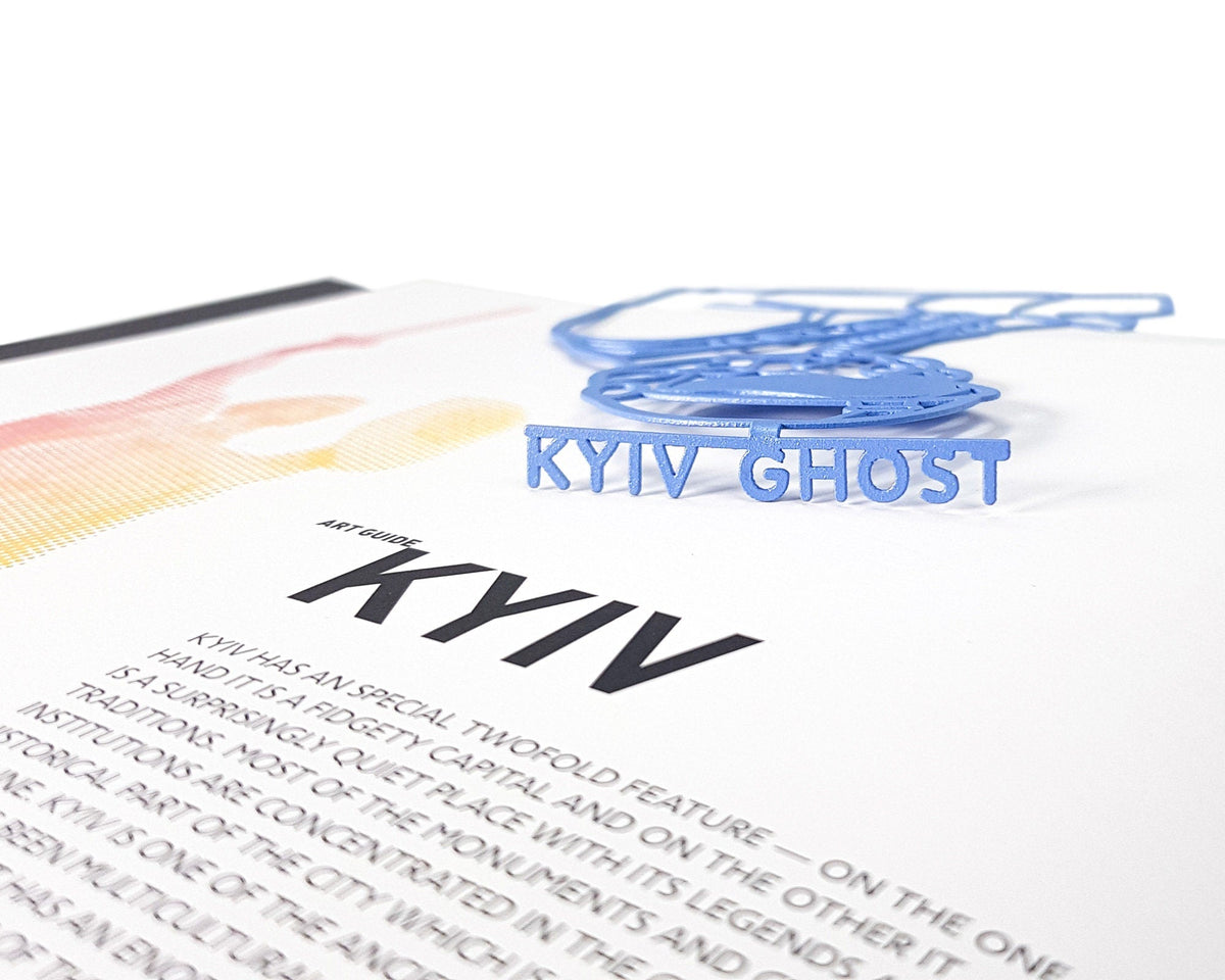Ghost of Kyiv metal bookmark in blue marking a page in an open book