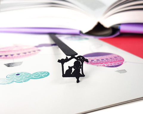 Girl Sitting with the Cat metal bookmark resting on the pages of an open book