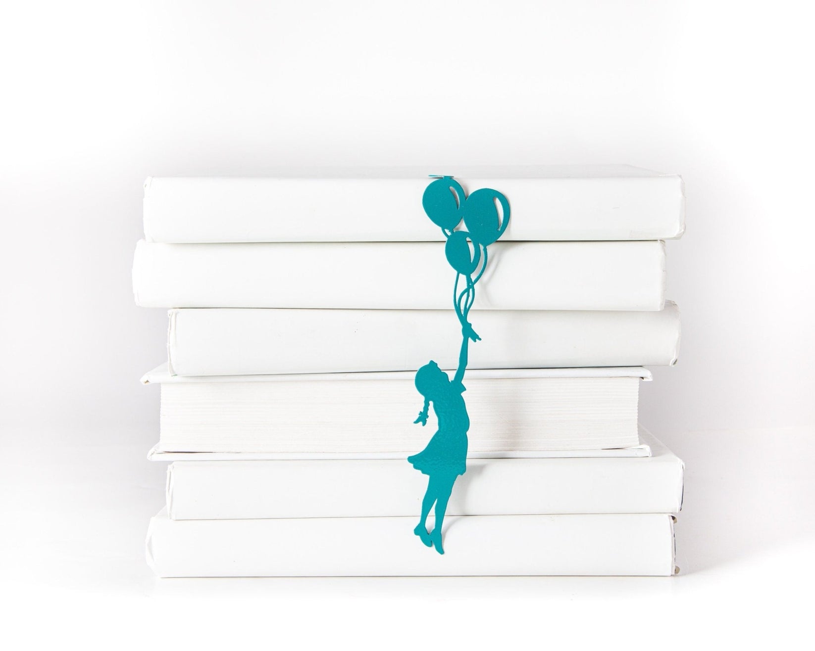Girl with Balloons metal bookmark in green shown with a stack of books