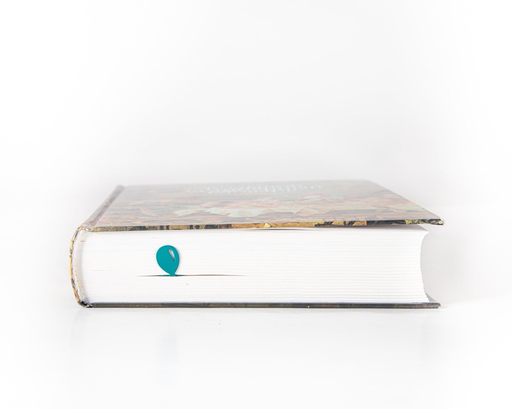 Girl with Balloons metal bookmark in green in a closed book, only its top showing above the pages