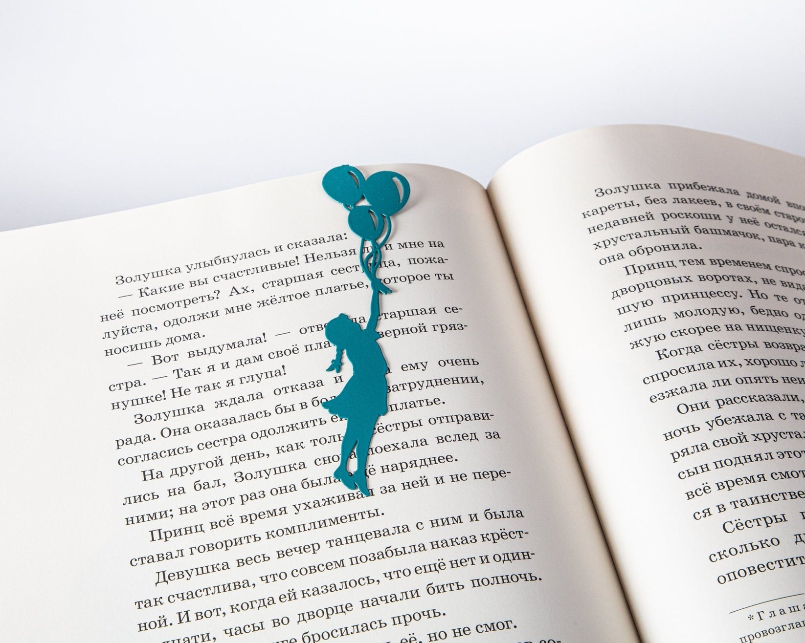Girl with Balloons metal bookmark in green resting on the pages of an open book