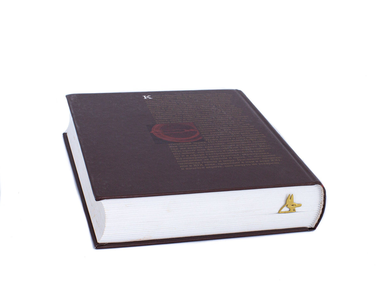 God of Death Anubis metal bookmark in gold clipped in a closed book, viewed from the side