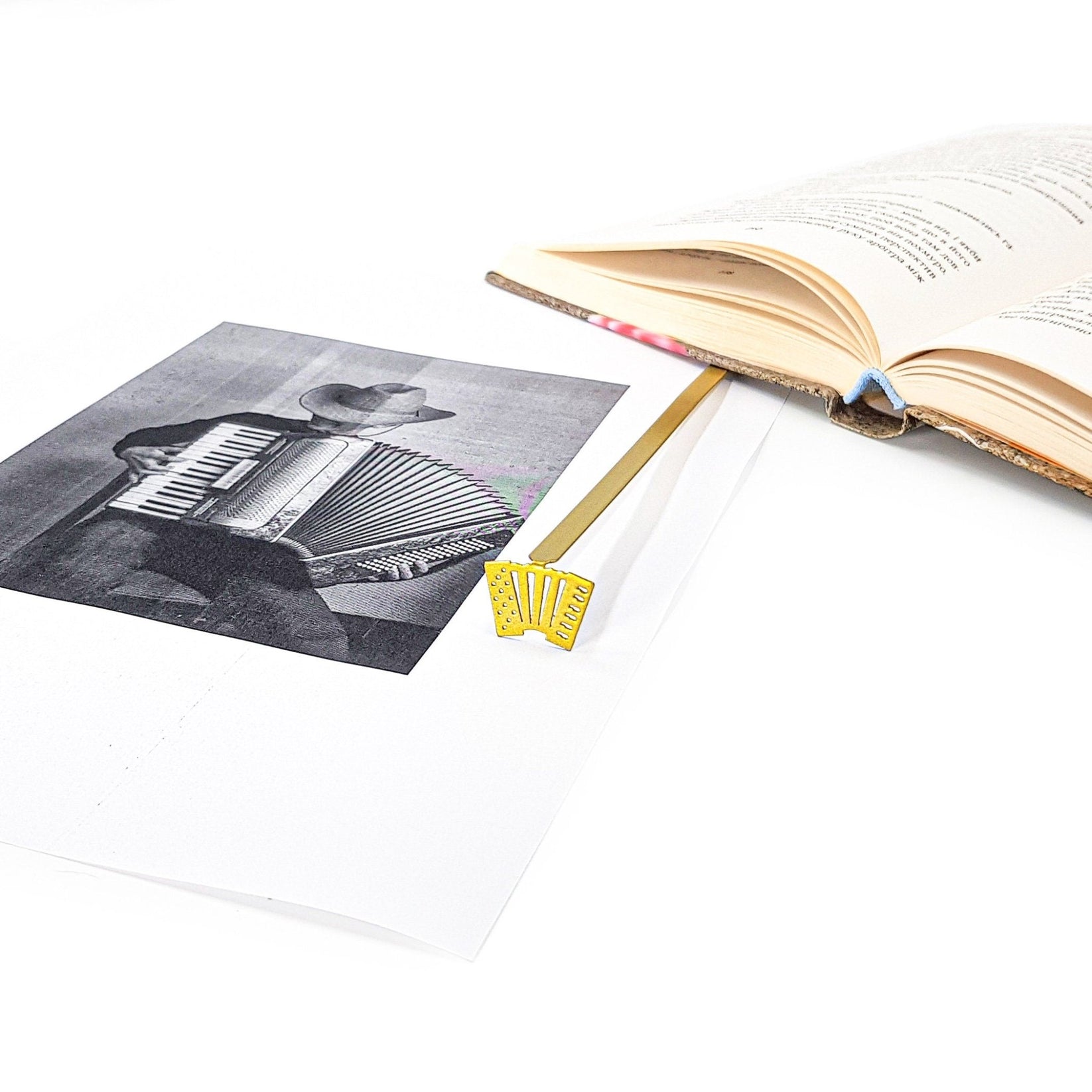 Golden Accordion metal bookmark on an illustrated page
