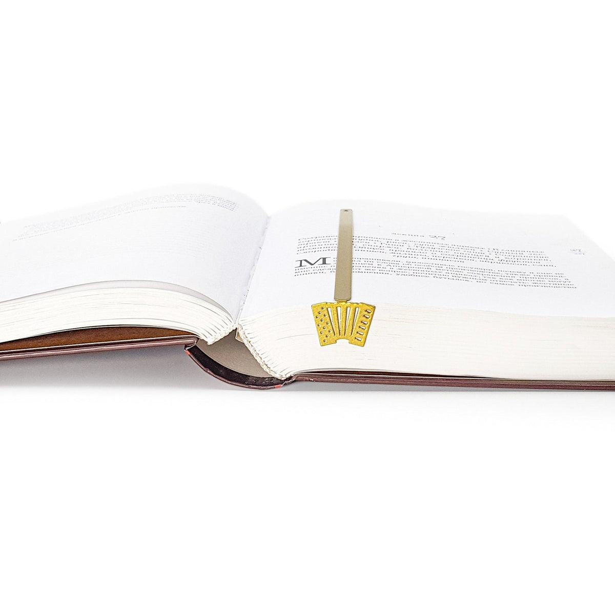 Golden Accordion metal bookmark in gold resting on the pages of an open book