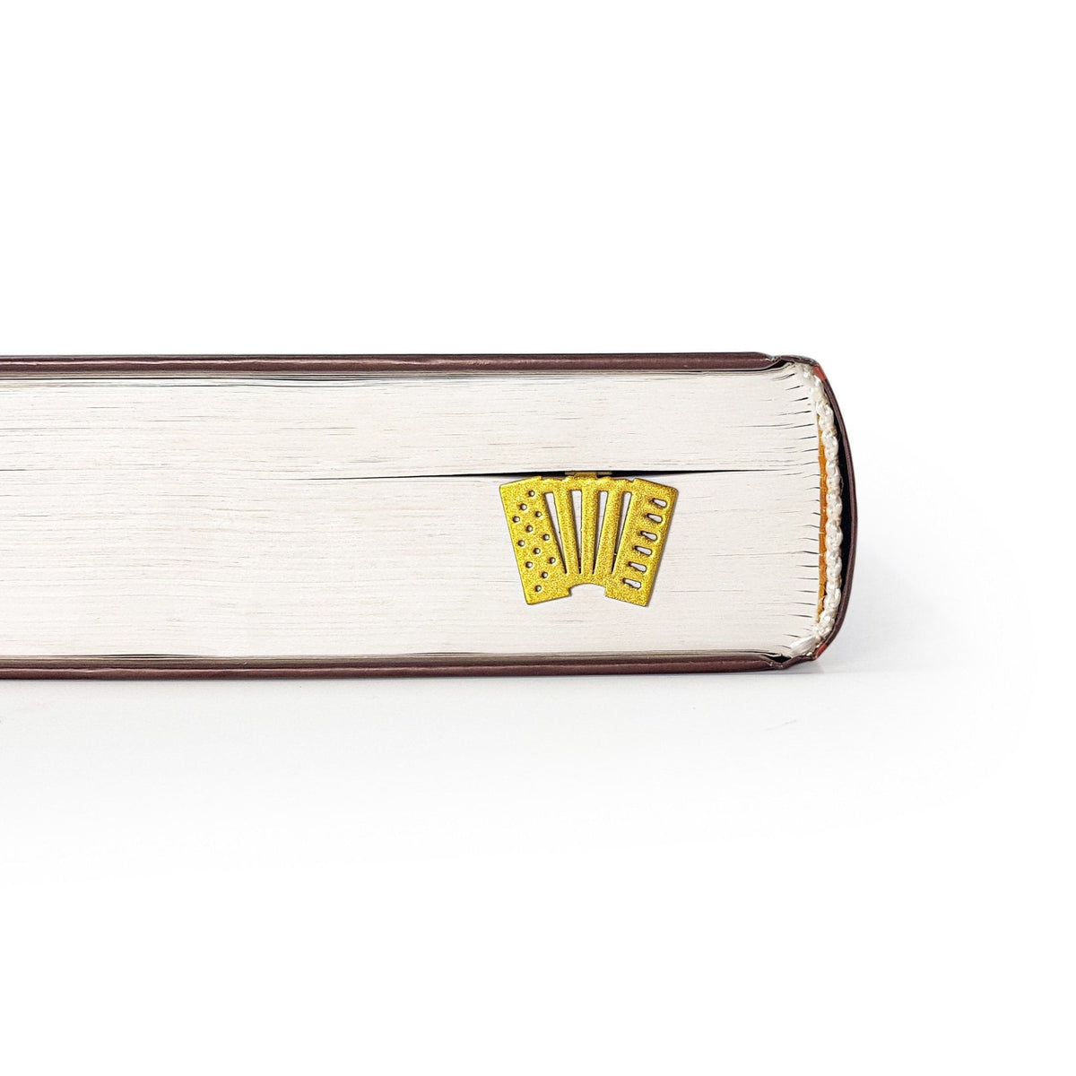 Golden Accordion metal bookmark in gold in a closed book, only its top showing above the pages