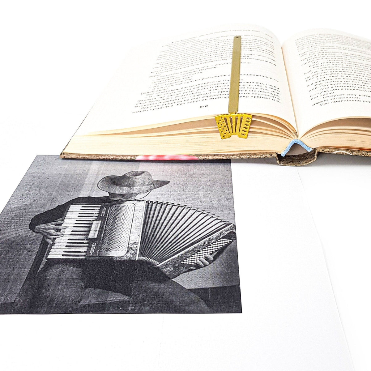 Golden Accordion metal bookmark in gold marking a page in an open book