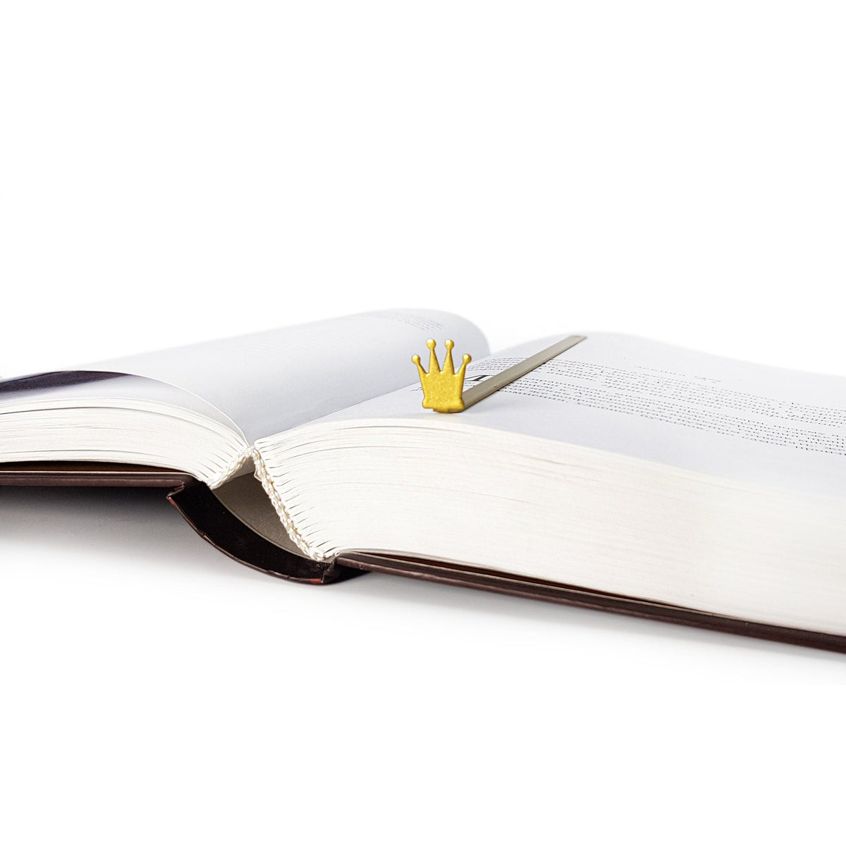 Golden Crown metal bookmark in gold marking a page in an open book