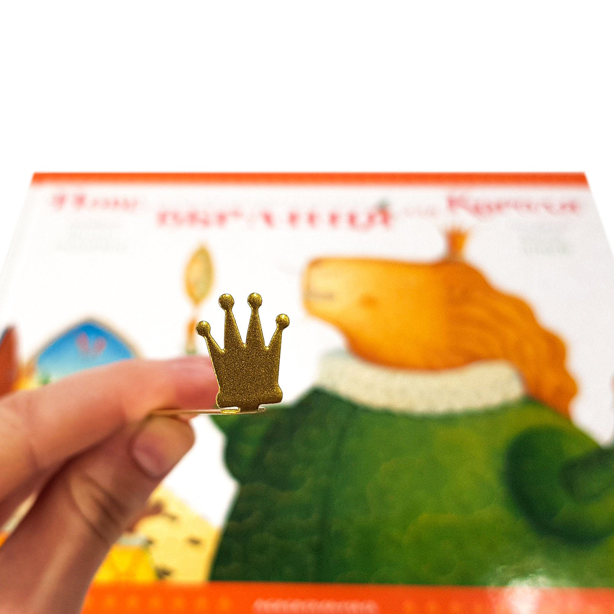 Golden Crown metal bookmark marking a page in an illustrated book