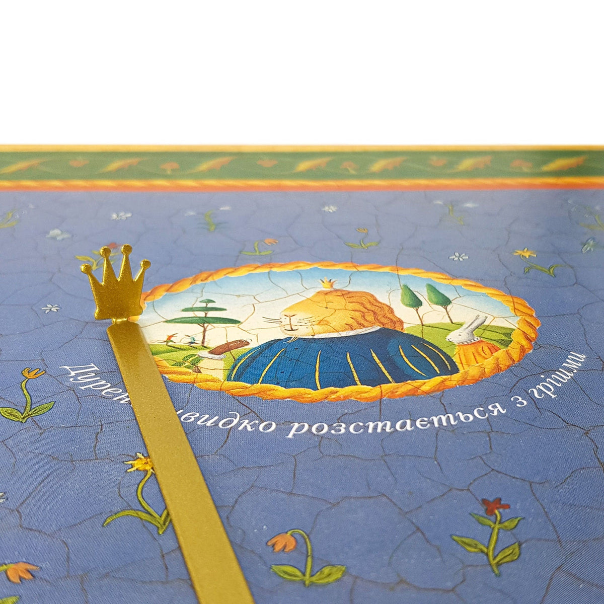 Golden Crown metal bookmark on an illustrated page