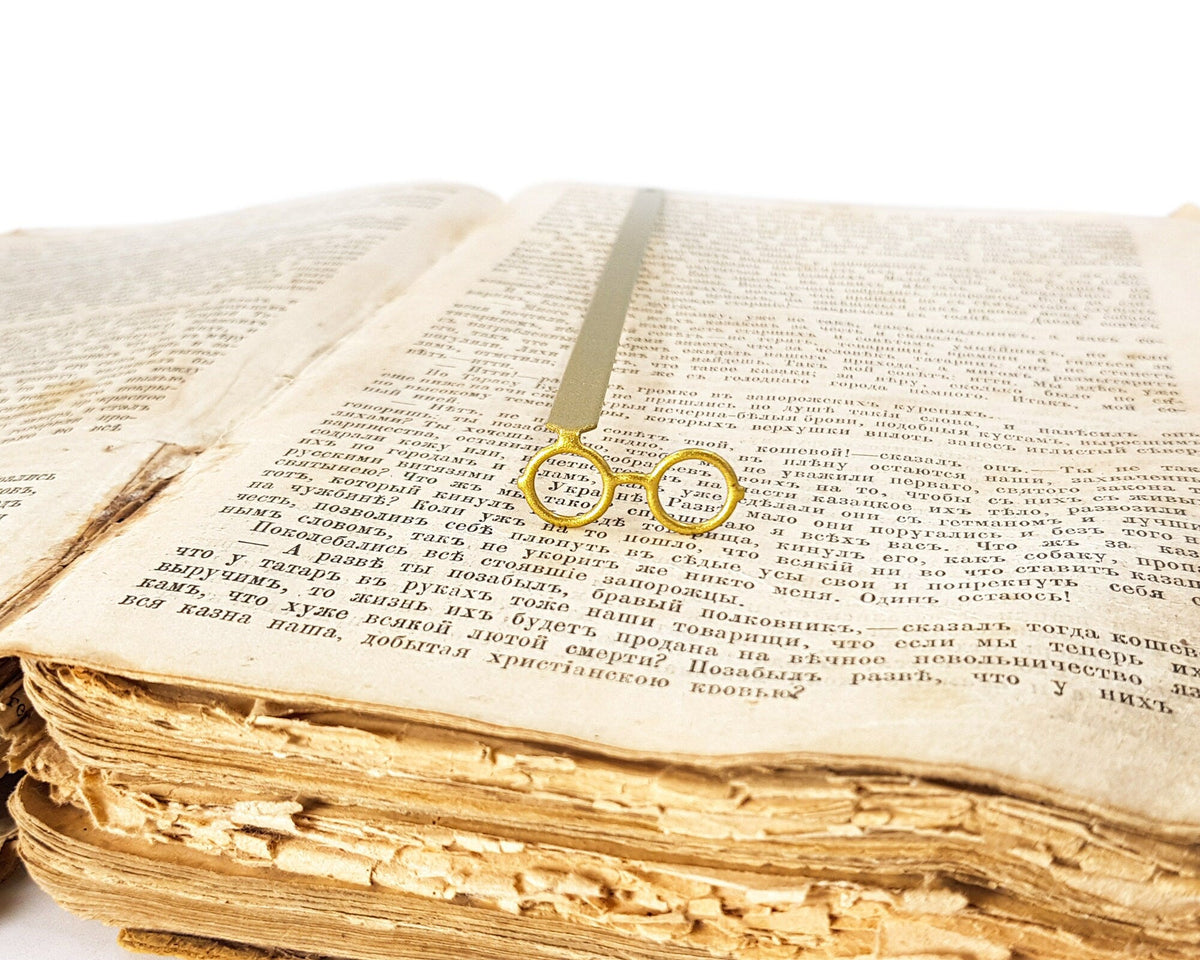 Golden Round Glasses metal bookmark in gold marking a page in an open book