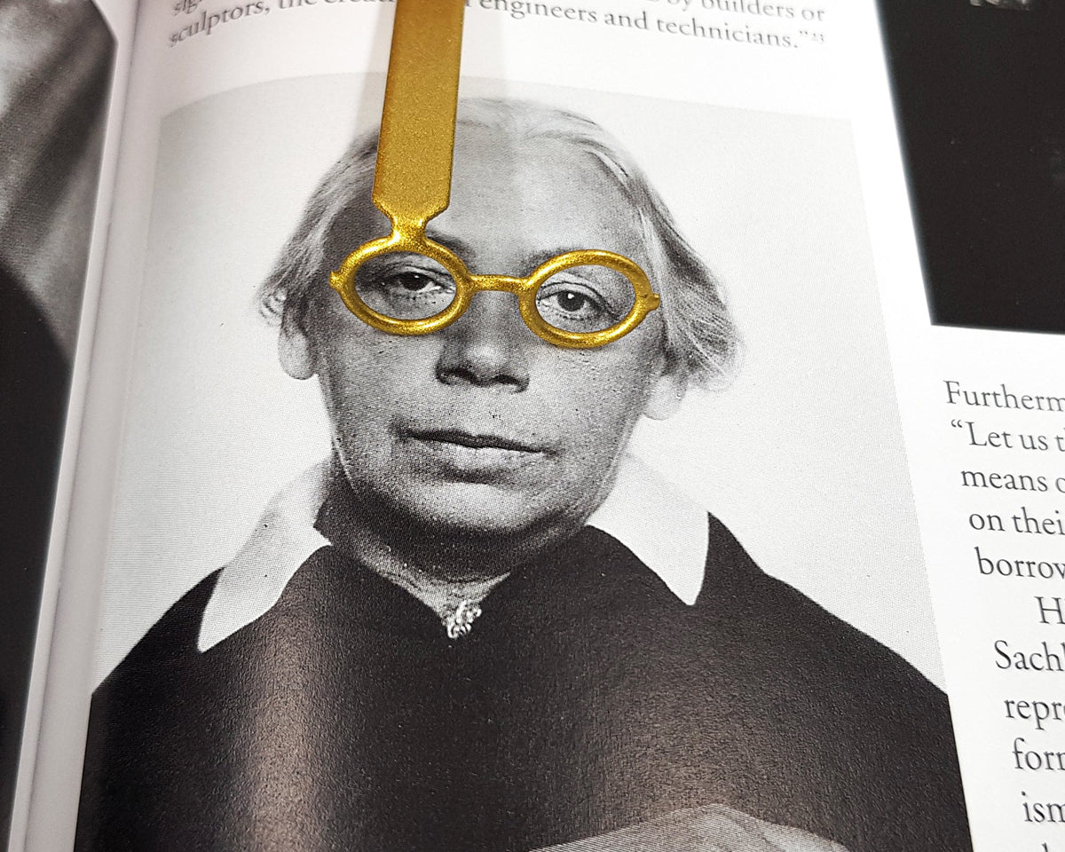 Golden Round Glasses metal bookmark marking a page in an illustrated book