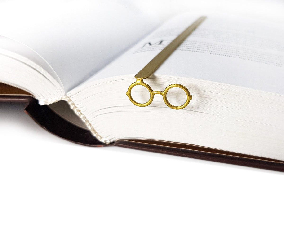 Golden Round Glasses metal bookmark in gold resting on the pages of an open book