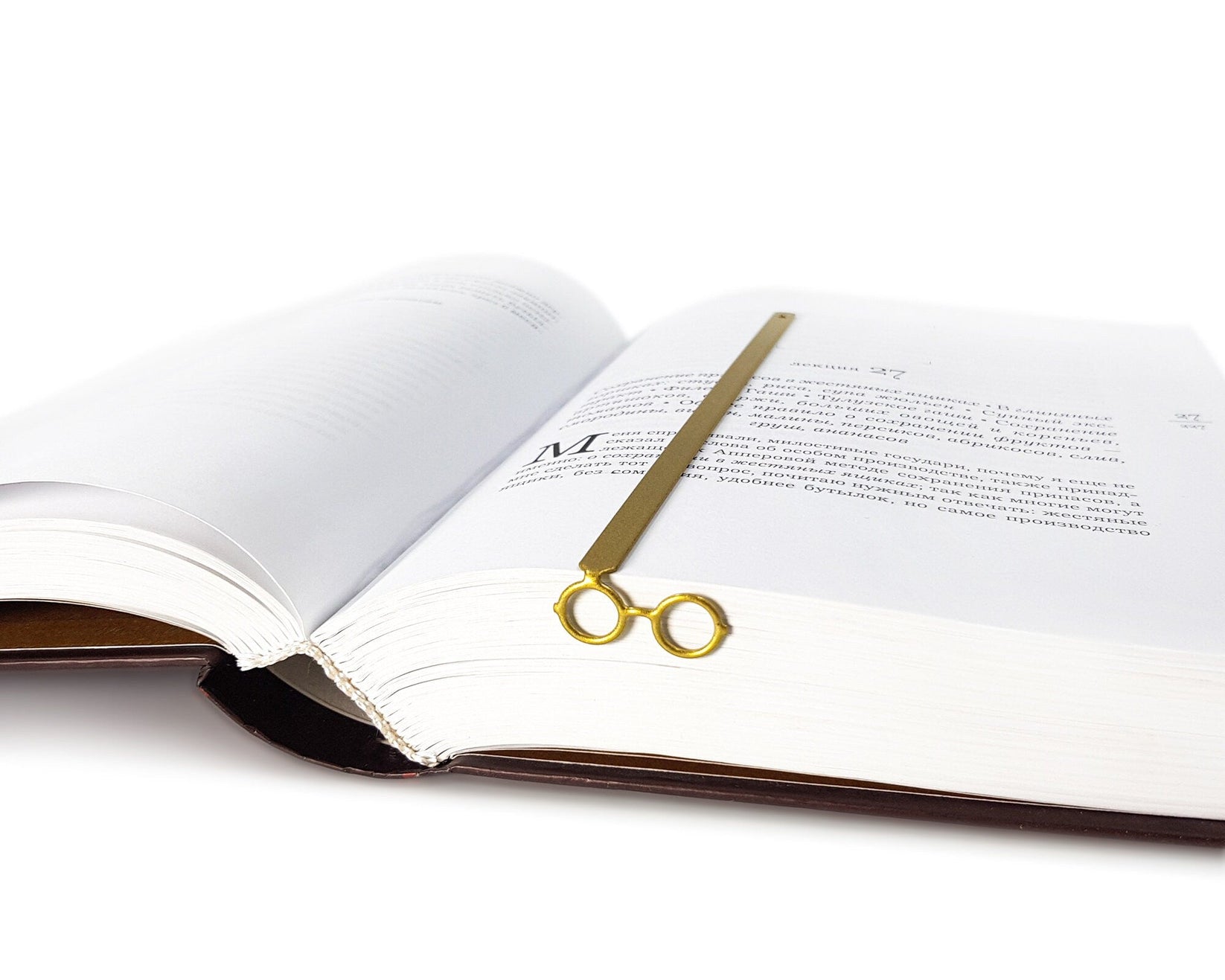 Golden Round Glasses metal bookmark in gold lying across the pages of an open book