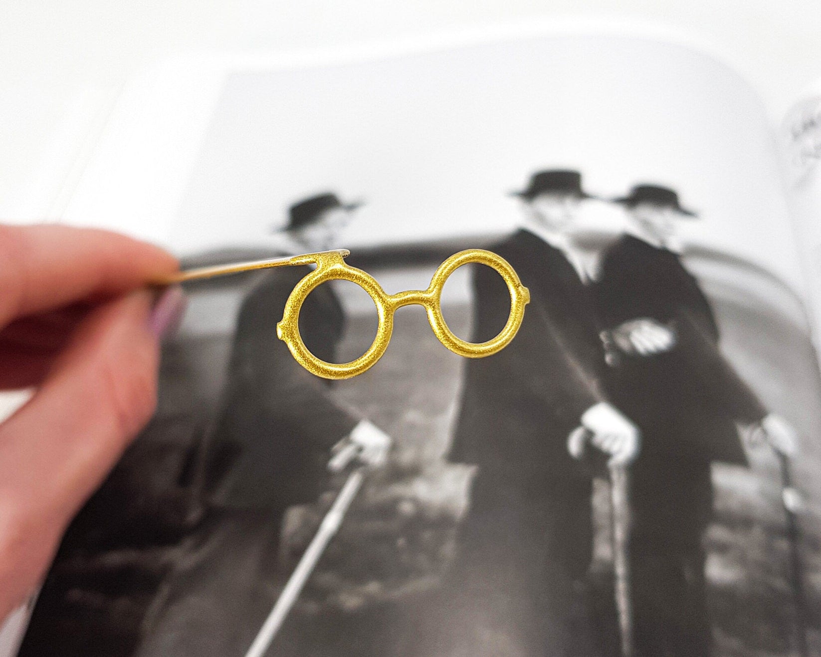 Golden Round Glasses metal bookmark marking a page in an illustrated book, view 4