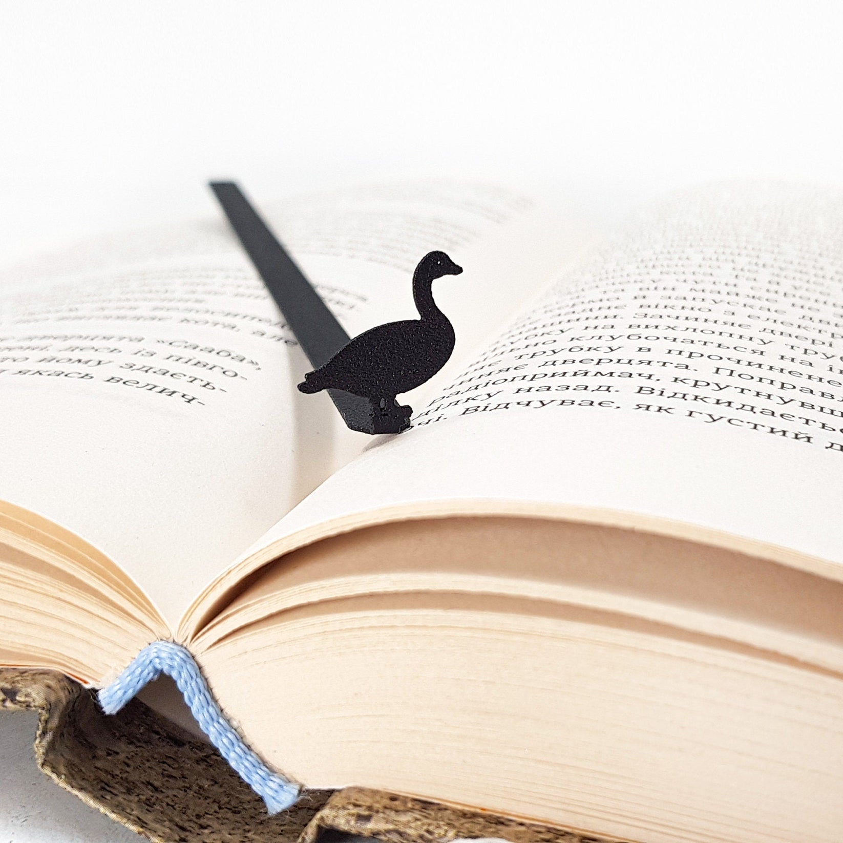 Goose metal bookmark marking a page in an open book