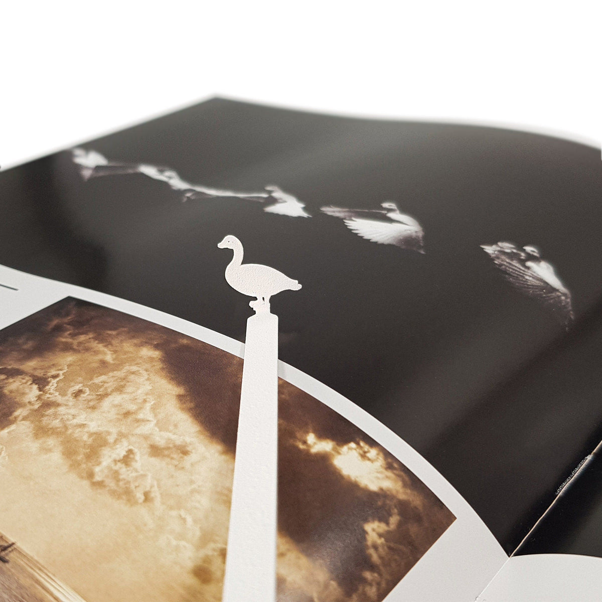 Goose metal bookmark in white marking a page in an illustrated book, view 4