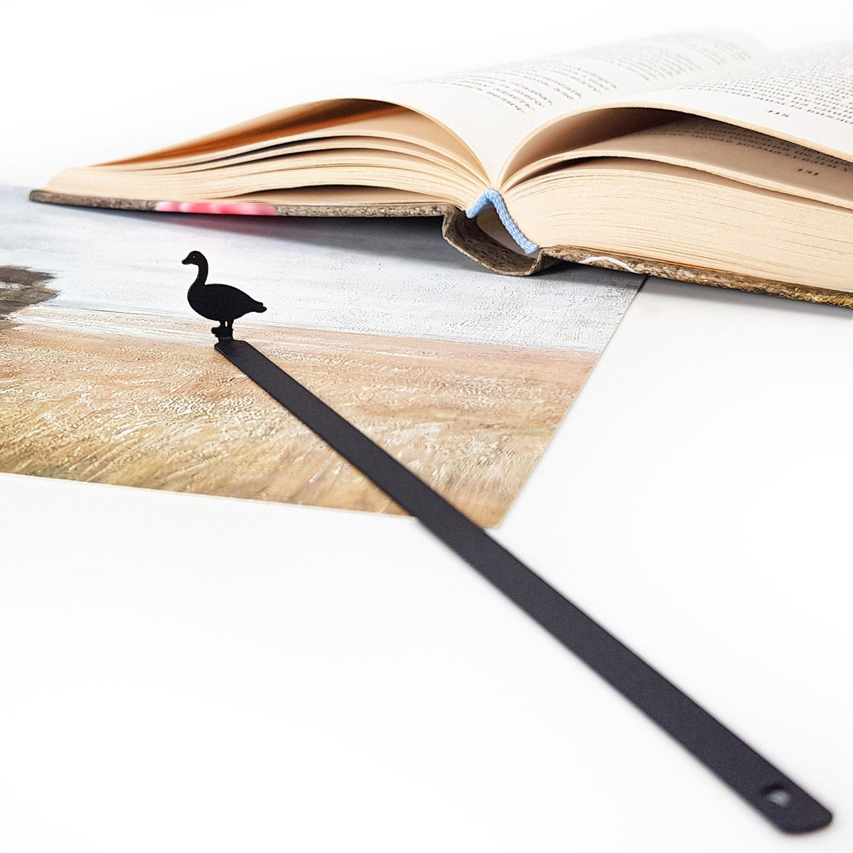 Goose metal bookmark placed on a colour illustration