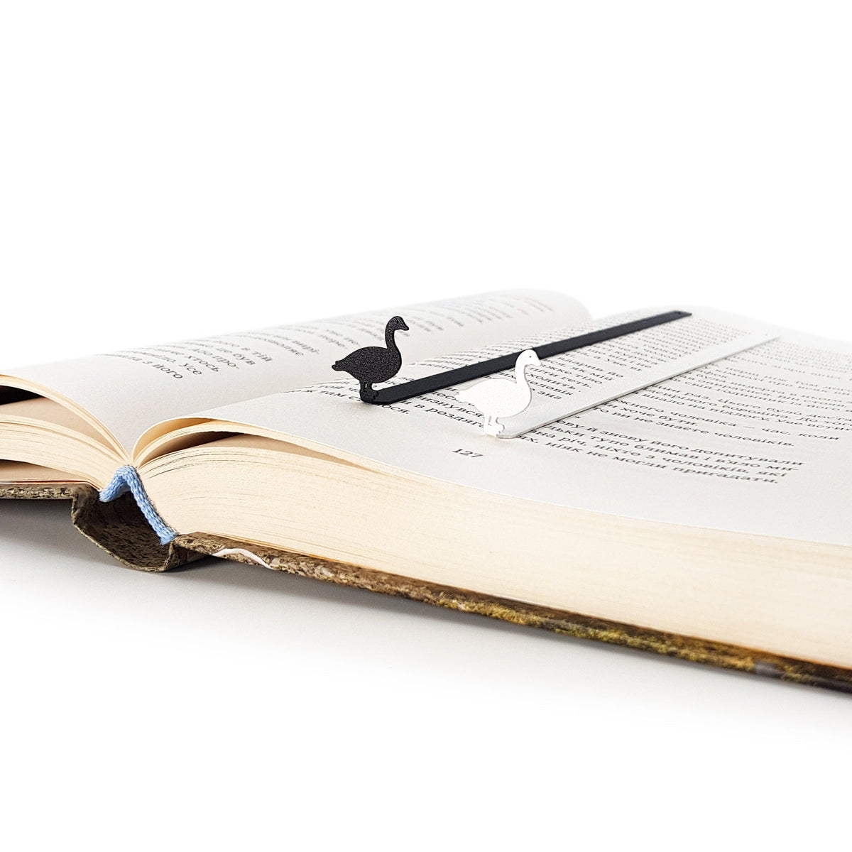 Goose metal bookmark lying across the pages of an open book
