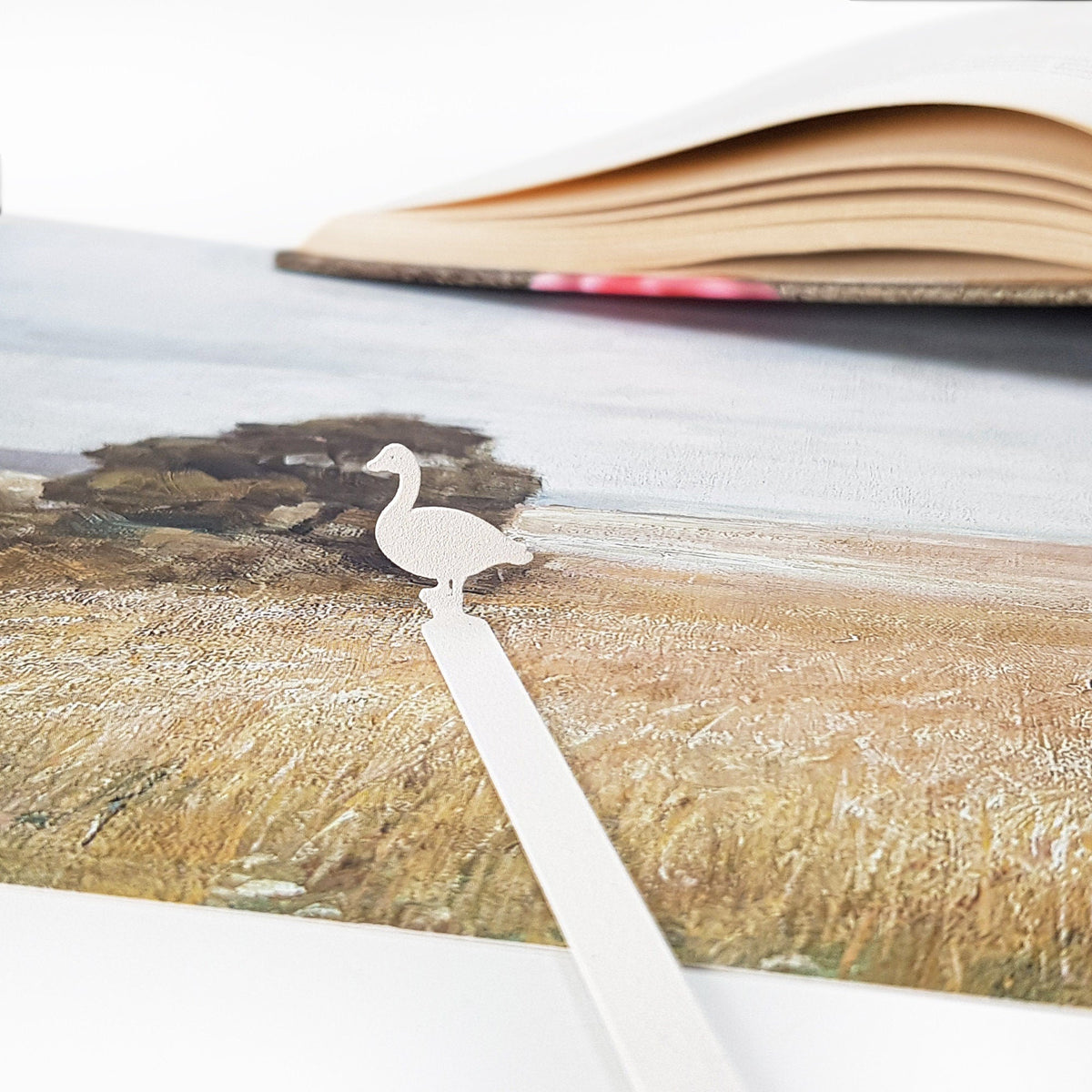 Goose metal bookmark in white on an illustrated page