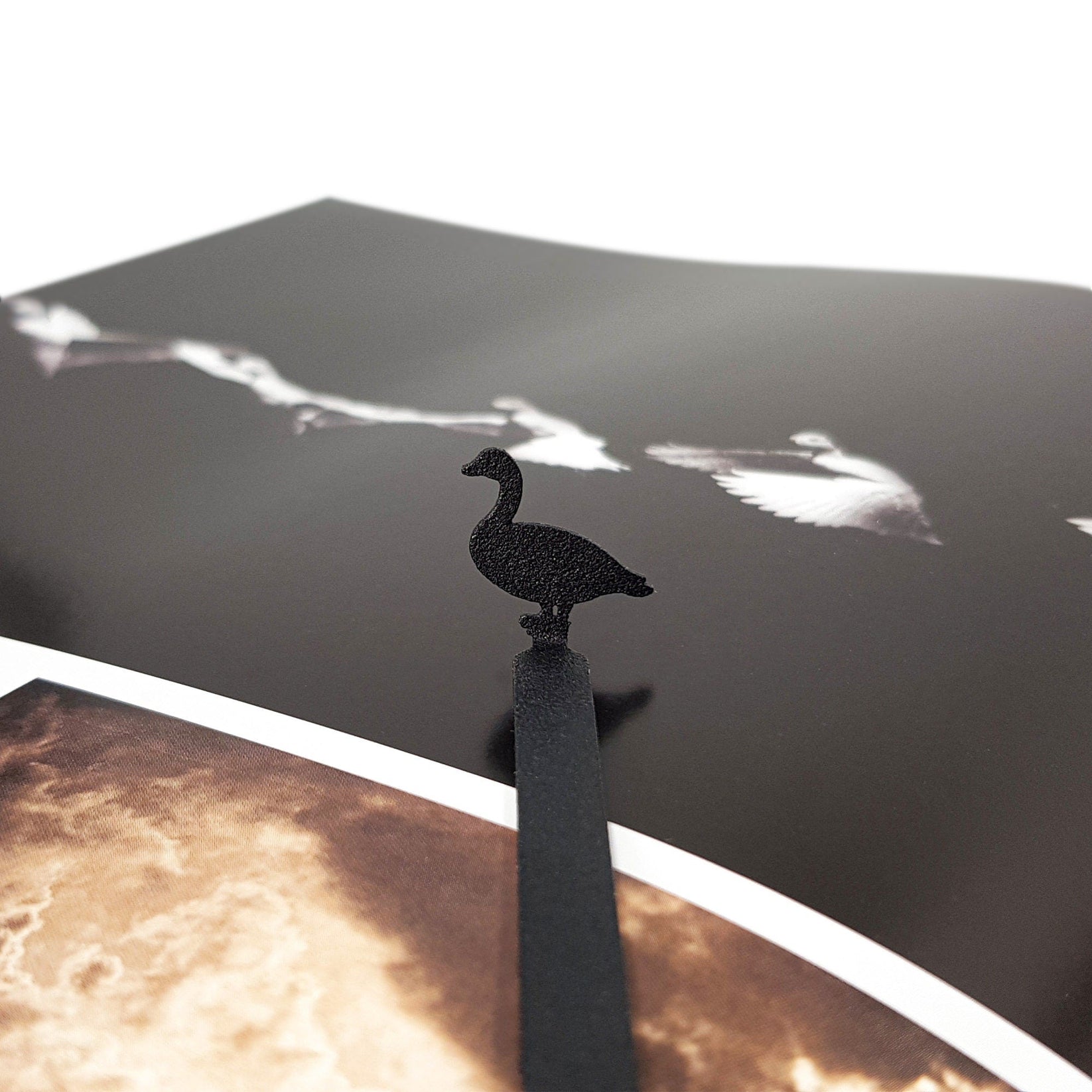 Goose metal bookmark in white on an illustrated page, view 5