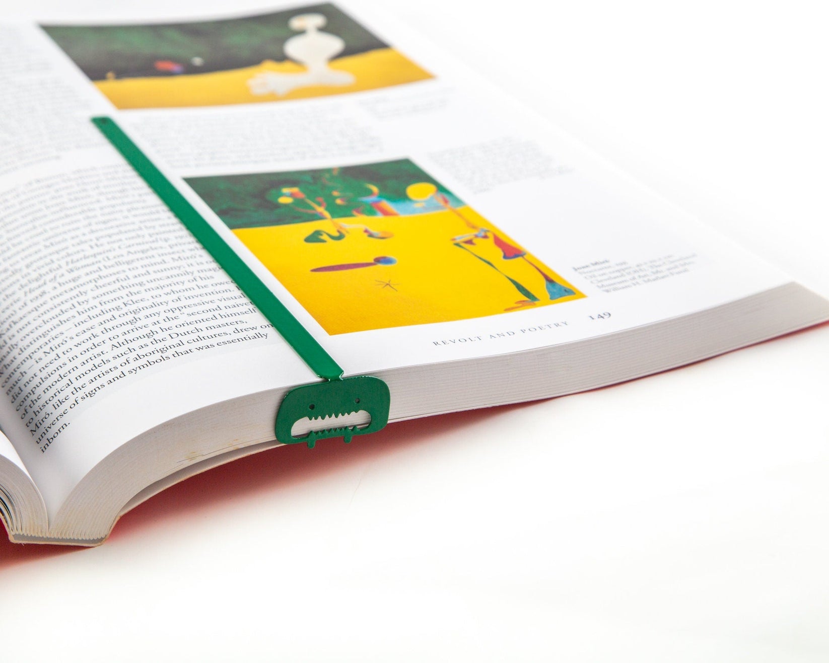 Green Screaming Monster metal bookmark marking a page in an illustrated book