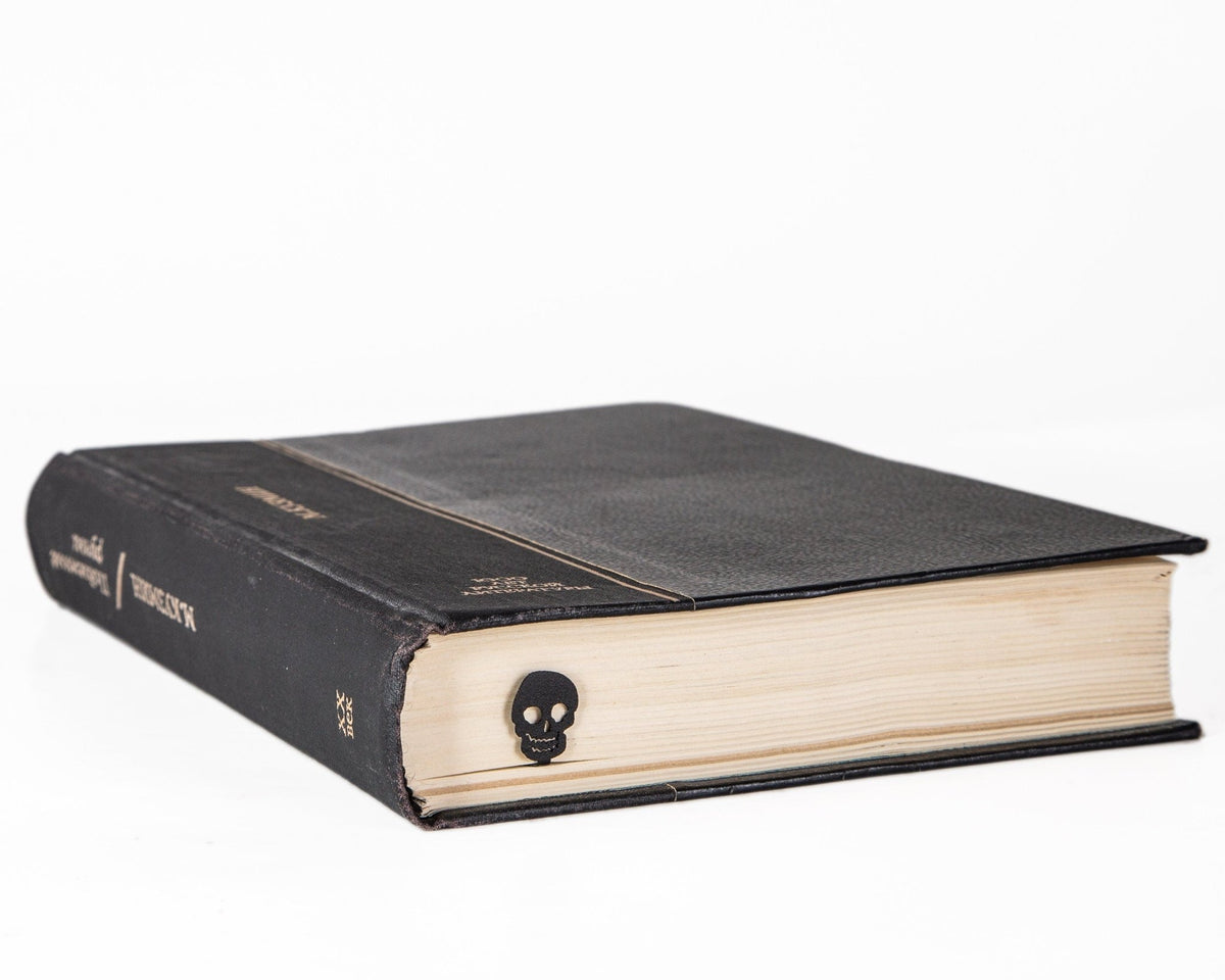 Grinning Skull metal bookmark seen from the edge of a closed book